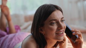 Lady sharing news in smartphone conversation lying on home bed closeup. Smiling woman wearing pajamas talking mobile phone at domestic weekend. Brunette discussing plans arrange meeting on cellphone. - Powered by Shutterstock - Get 15% off with code: PIKWIZARD15