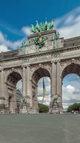 Hyperlapse of the Cinquantenaire Arcade in Jubelpark, Brussels, Belgium. The memorial triumphal arch stands tall under dramatic clouds timelapse, symbolizing Belgian history and independence.