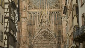 Tilt shot of the Strasbourg Cathedral ornate Gothic facade and spire, intricate stonework, arcs and rose window. Overview of Gothic cathedral surrounded by medieval buildings under a cloudy sky. - Powered by Shutterstock - Get 15% off with code: PIKWIZARD15