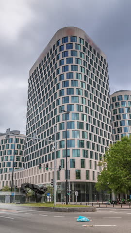 Timelapse of traffic and modern office buildings in the business district on Boulevard Baudouin, Brussels, Belgium. Contemporary towers near an intersection and park under a cloudy sky