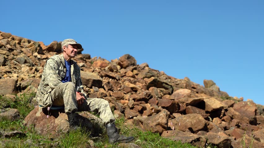A man sits and enjoys nature on a rocky mountain ridge