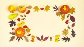 Thanksgiving greeting card. Beautiful frame of autumn leaves, orange pumpkins, ripe apples, pears, rowan berries and acorns. Light yellow background. Stop motion animation. Flat lay. Copy space. - Powered by Shutterstock - Get 15% off with code: PIKWIZARD15