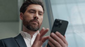 Calm Caucasian 40s businessman using mobile phone in office looking out window male specialist entrepreneur pensive business man chatting smartphone online e-commerce modern technology checking emails - Powered by Shutterstock - Get 15% off with code: PIKWIZARD15