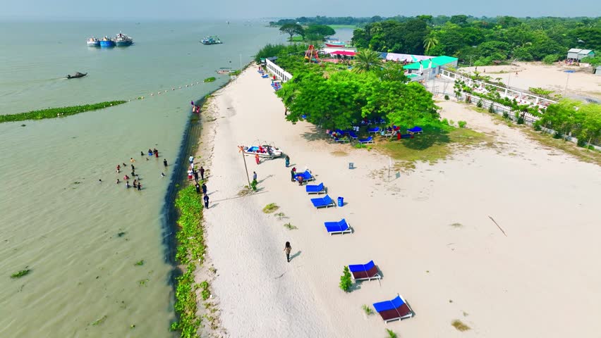 Aerial view of a crowded beach with lounge chairs and boats on the water under a clear sky Chandpur Bangladesh
