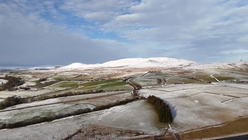 A scenic winter landscape featuring snow-covered hills and fields, under a partly cloudy sky, showcasing the beauty of nature.