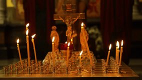 burning candles in the temple, wax candles lit against the background of a cross with a crucifix, the concept of christian religion, prayers for the salvation of the soul, soft focus - Powered by Shutterstock - Get 15% off with code: PIKWIZARD15