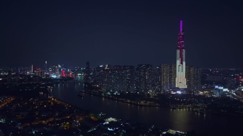 Aerial night view Ho chi minh city and Saigon river in Vietnam, illuminated of bridge and business center with skyscrapers.