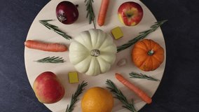 In the center, on a black stone background, a round wooden board with fresh pumpkin, zucchini, carrot, apple, orange, onion, garlic, bouillon cubes and rosemary sprigs is spinning to the left. Flat cl - Powered by Shutterstock - Get 15% off with code: PIKWIZARD15