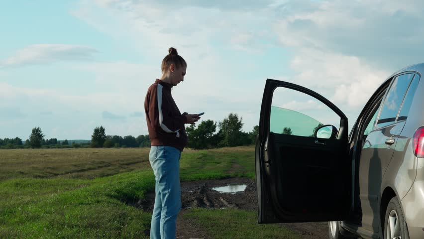 The woman's car broke down in a field on the way to the village. The woman tries to call for help on the phone, but there is no connection. Rural area.