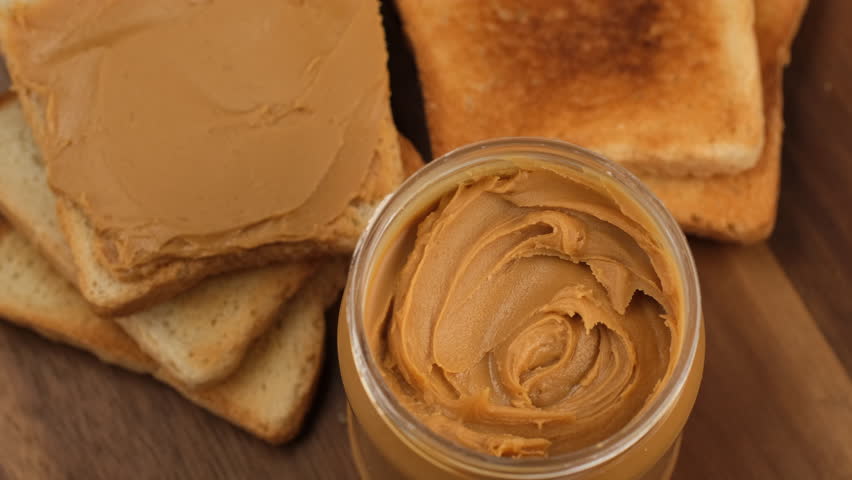 Jar with peanut butter and toast bread with peanut butter, rotation