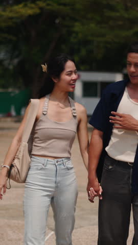 Young asian couple walking together, holding hands in park, sharing intimate moment
