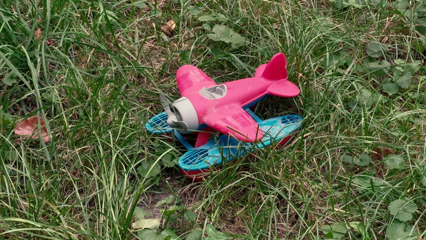 Pink Toy Seaplane Forgotten in Grass on Playground: Children