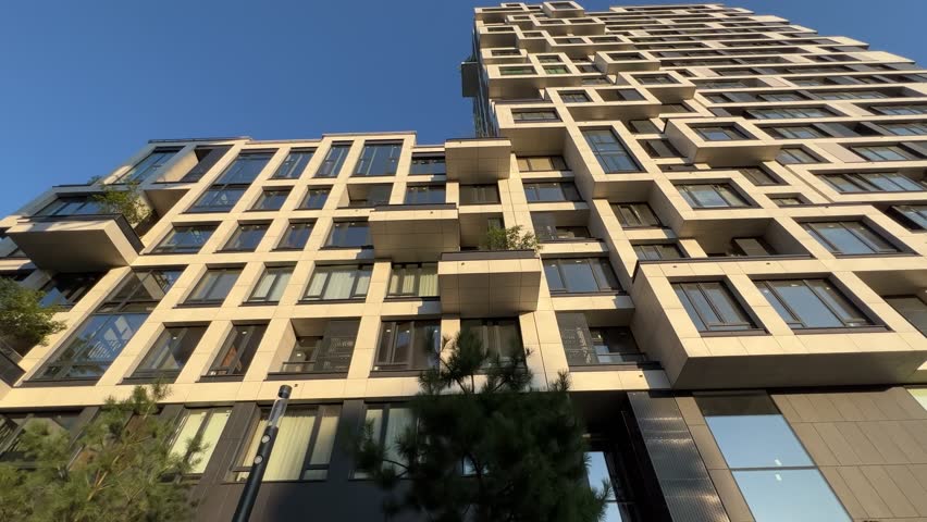 Modern Residential Building Low-Angle View: Luxury Multi-Story Complex with Asymmetric Facade Design | Premium Stone Towers with Floor-to-Ceiling Windows and Commercial Ground Floor