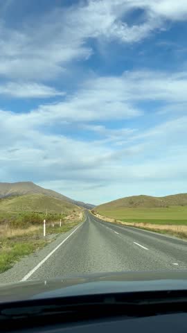 Serene drive through open road under vast sky with rolling hills. Travel. New Zealand