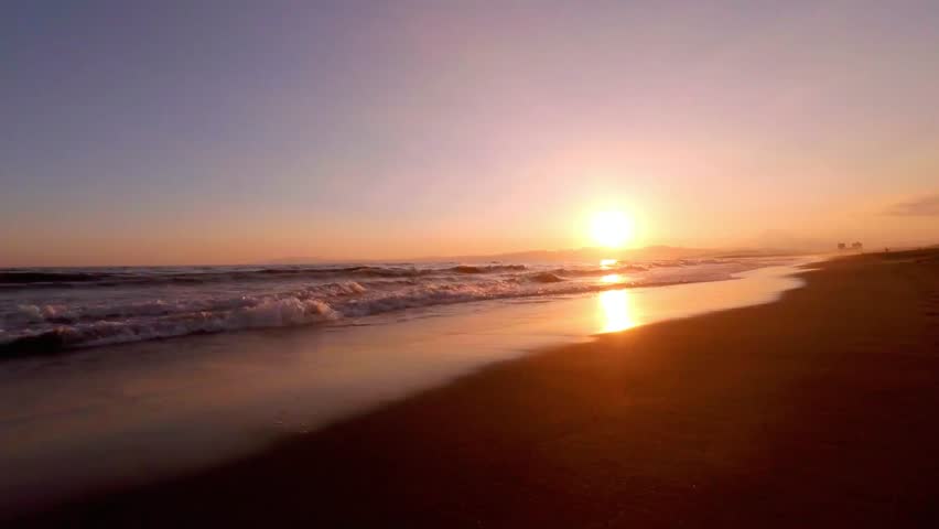 Golden sunset over the sea with waves gently lapping on the sandy beach