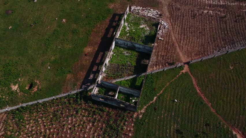 Aerial of shattered abandoned building surrounded by fields and nature in Abuja, Nigeria.