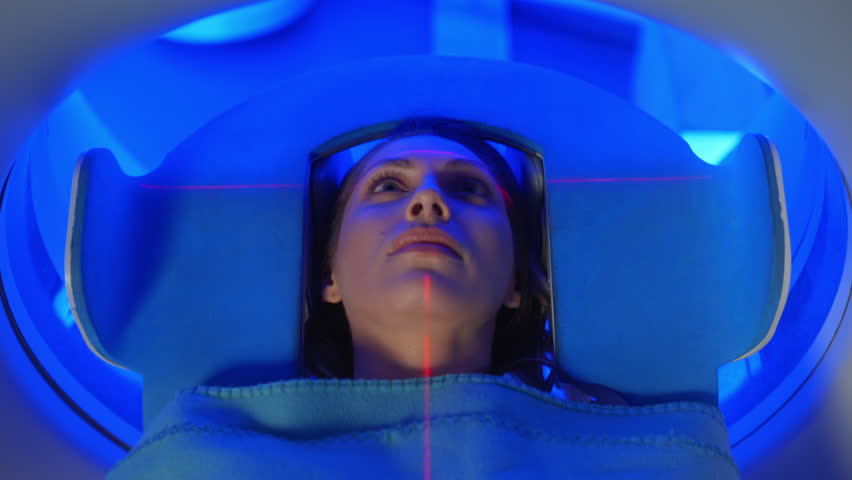 Close-up Portrait Women patient on CT MRI scanner, Bed is Moving Inside the Machine While it Scans Her Body and Brain. In Medical Laboratory with High-Tech Equipment. Top Down View