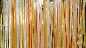 Colorful satin ribbons hang like wall and sway in wind in sunbeams. Festive background in warm colors at party and people passing through ribbons. Atmospheric bright decoration. - Powered by Shutterstock - Get 15% off with code: PIKWIZARD15