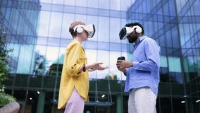 Two people wearing VR headsets stand outdoors in front of a modern building, gesturing as if in a virtual environment. - Powered by Shutterstock - Get 15% off with code: PIKWIZARD15