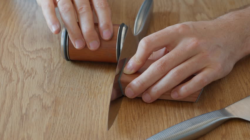 A man easily flips a knife on its magnetic holder to sharpen the other side. This convenient feature of the rolling knife sharpener system ensures a quick and easy process. Includes original audio.