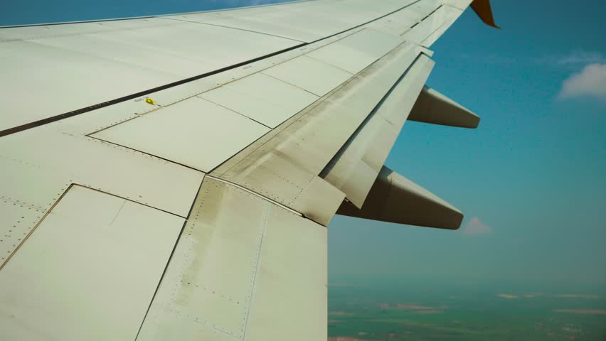 Passenger jet turning after takeoff while retracting flaps. Aircraft accelerating and adjusting flaps while gaining altitude. Airliner banking in climb out as wing surfaces moving in