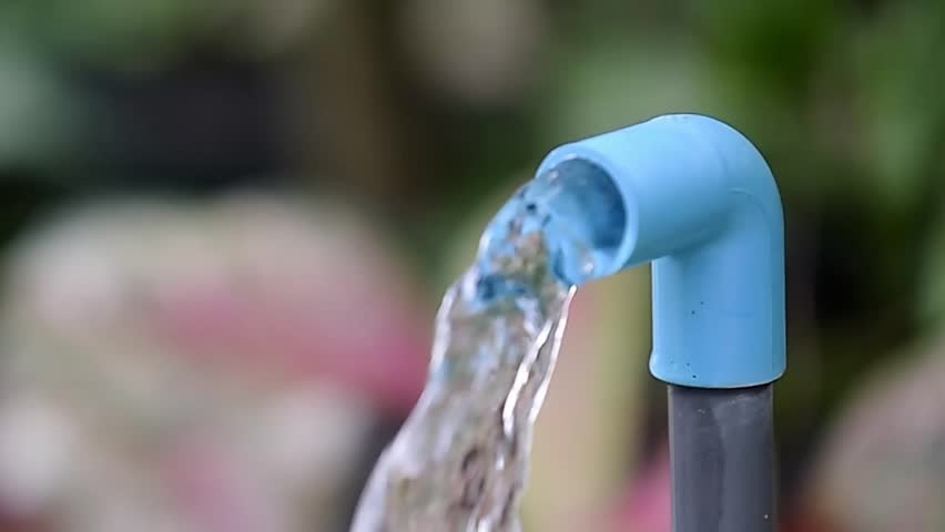 Water Flowing from Plastic Pipe: Capturing the gentle cascade of clear water flowing from a blue plastic pipe. A macro shot of this essential resource.
