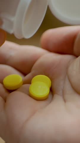 Yellow pills falling from bottle into man open hand. Promoting wellness, medication, or health management services