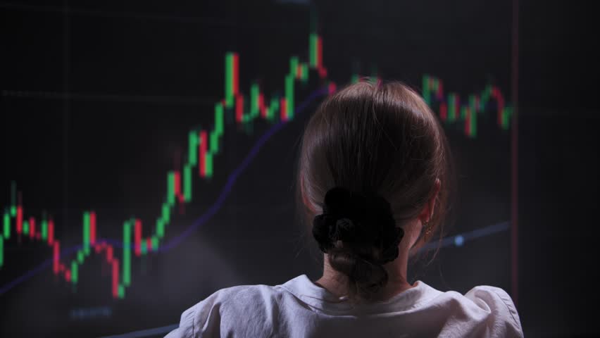 Woman in front of a big screen analyzes the current situation on stock market