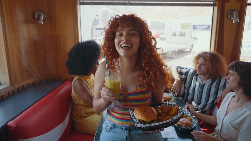 Multiethnic group of friends having meal at 80s vintage diner restaurant - Multicolored young people bonding and having fun, eating in an american fast food burger house	
