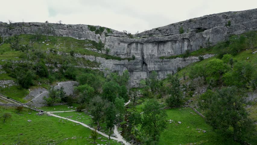 Malham Cove in the North Yorkshire Dales in the north of England. Malham Cove is a large curved limestone formation formed by a waterfall carrying meltwater from glaciers in the last Ice Age.