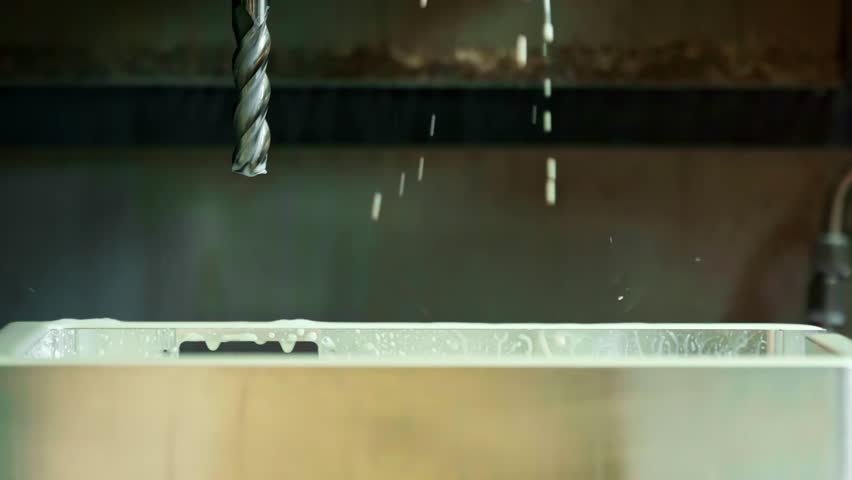 Water drips from machined metal bit in factory environment in ultra slow motion