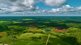 A stunning aerial time-lapse captures fast-moving clouds casting dynamic shadows across a vast and beautiful Latvian landscape of lush green forests, fields, and lakes. - Powered by Shutterstock - Get 15% off with code: PIKWIZARD15