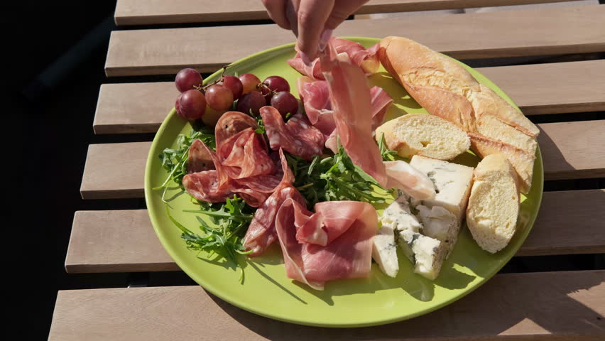 a woman prepares a Charcuterie plate with appetizers for dinner or an aperitif, serves salami, prosciutto, cheeses and berries