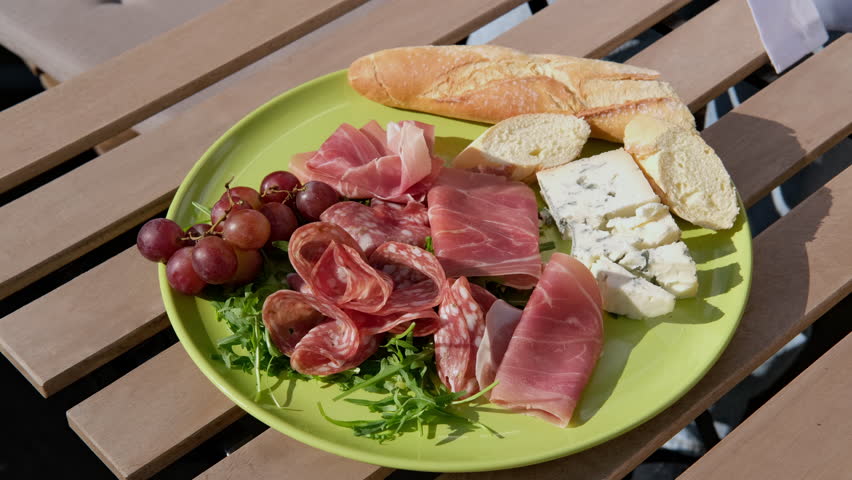 a woman prepares a Charcuterie plate with appetizers for dinner or an aperitif, serves salami, prosciutto, cheeses and berries