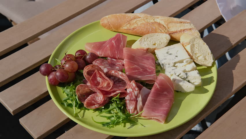 a woman prepares a Charcuterie plate with appetizers for dinner or an aperitif, serves salami, prosciutto, cheeses and berries