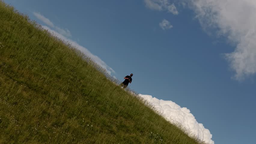 Drone rise with camera rotation showing hiker on top of Monte Baldo as thunderstorm clouds emerge in parallax, Italian Alps, Italy