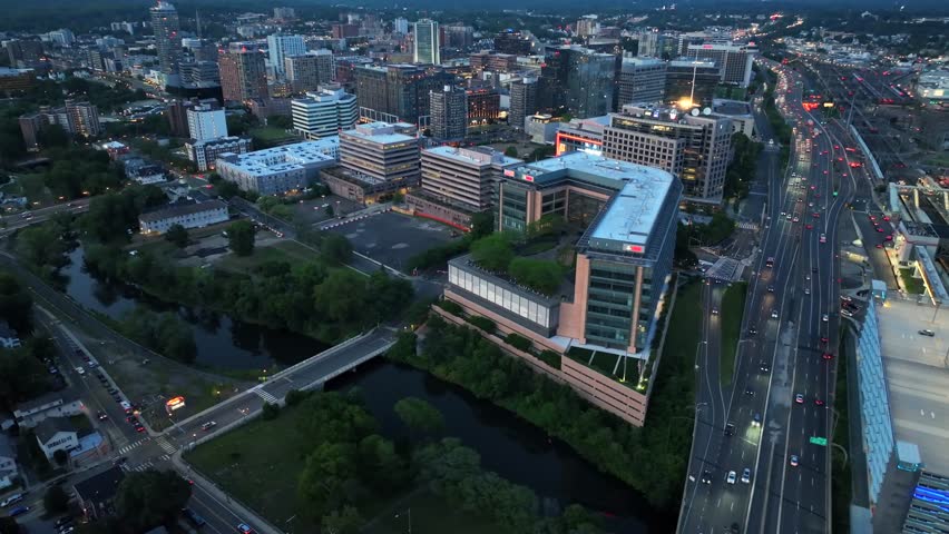 Stamford , United States - 08 03 2025: Downtown Stamford, Connecticut, with modern high-rise offices, glass façades, illuminated streets and the Mill River running through urban landscape.Aerial night