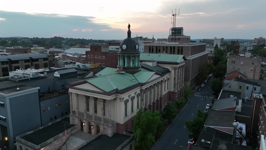 Aerial approaching shot of lancaster county courthouse with cupola and clock. Dusk scene in downtown of city. Houses and apartments in small town of America.