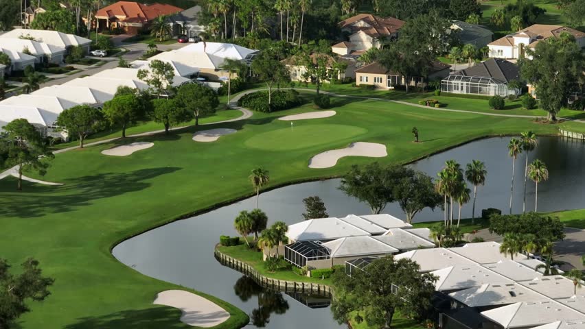 Lake, well-maintained golf course and luxury houses in golf club of Brandenton, Florida. Sunset time. Aerial wide shot. Expensive housing area in America.