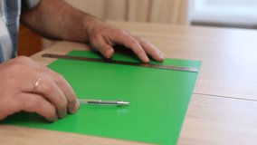 Hands drawing cutting lines on colored cardboard, crafting template for paper model, DIY project preparation. - Powered by Shutterstock - Get 15% off with code: PIKWIZARD15