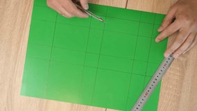 Hands drawing cutting lines on colored cardboard, crafting template for paper model, DIY project preparation. - Powered by Shutterstock - Get 15% off with code: PIKWIZARD15