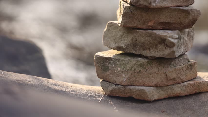 Stacked Rocks Near River Tilt Up With Background Blurred