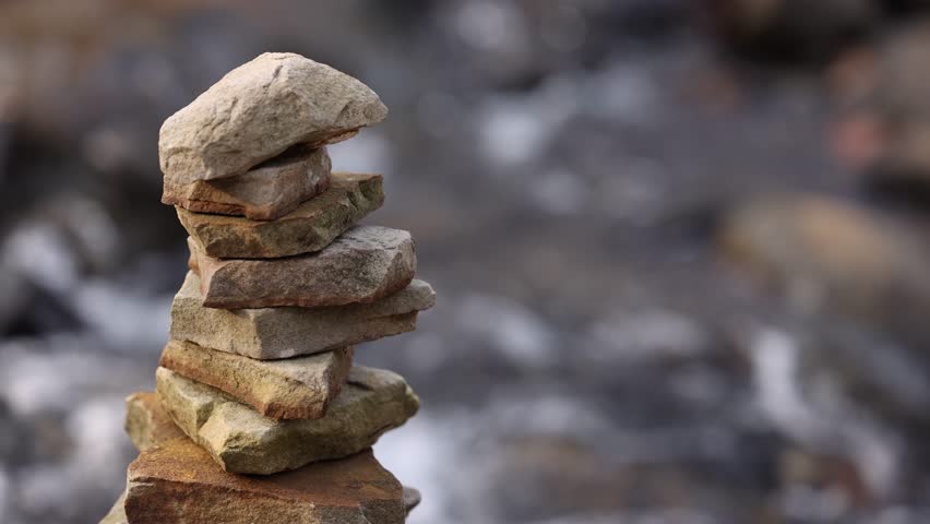 Zoomed In View Of Stacked Rocks With River Flowing Behind