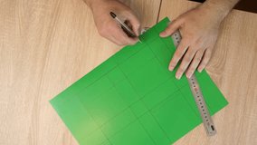 Hands drawing cutting lines on colored cardboard, crafting template for paper model, DIY project preparation. - Powered by Shutterstock - Get 15% off with code: PIKWIZARD15