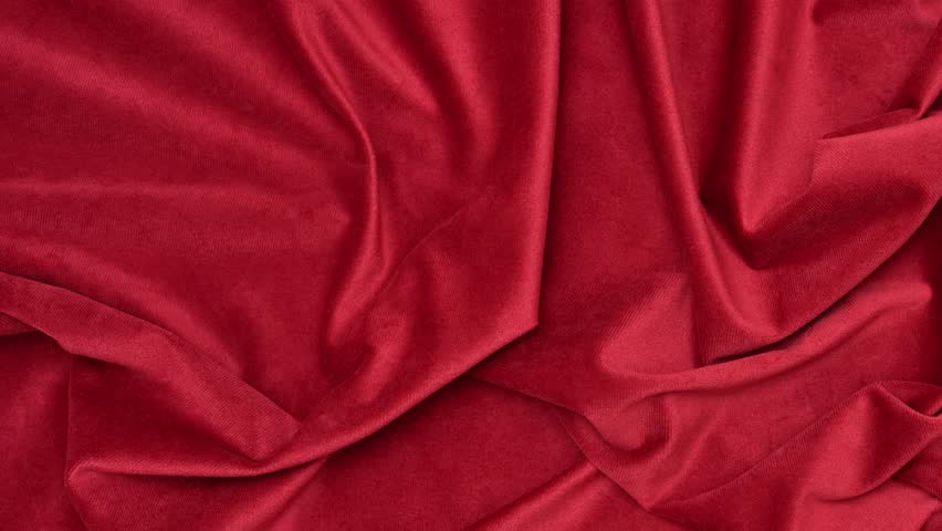 Red velvet fabric texture with soft folds. Red fabric background of soft and smooth textile material. Fabric texture for design and decoration. Top view.