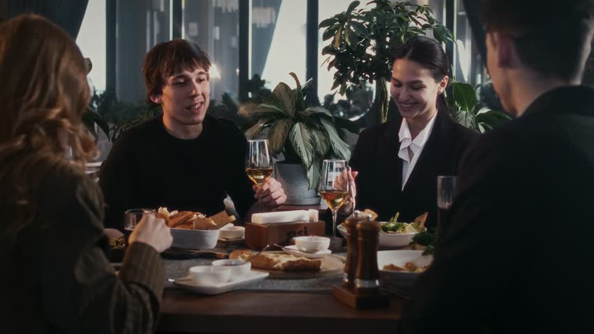 Friendly company of young guys and girls at a business meeting in an informal setting in a restaurant at a table