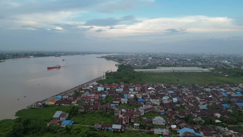 View of the Kapuas River, Pontianak City, West Kalimantan Province, Indonesia in the afternoon with cloudy skies and visible ships, villages and flying kites