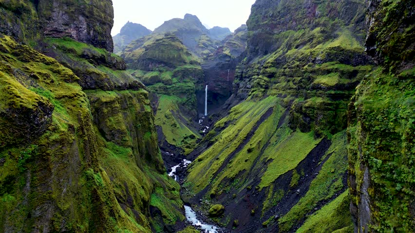 Witness the majestic Mulagljufur Canyon, where towering green cliffs embrace a winding river and cascading waterfall. This dramatic location showcases Icelands natural wonders in breathtaking detail.