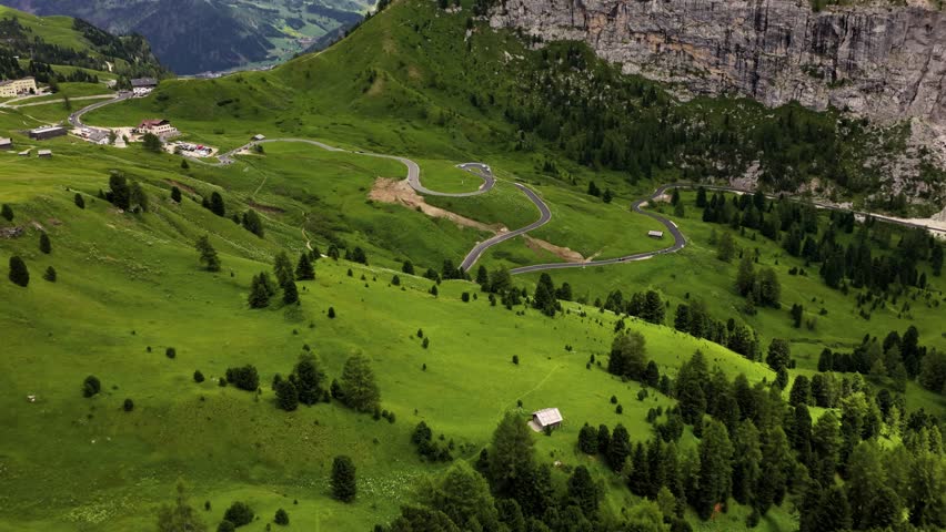 Curvy mountain road in Passo di Giau, Dolomites, Italy, aerial view of alpine switchbacks and green hills