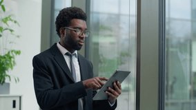 Thoughtful African American businessman in office concentrate using digital tablet looking out window focused business male man guy using technology device thinking planning strategy professional work - Powered by Shutterstock - Get 15% off with code: PIKWIZARD15